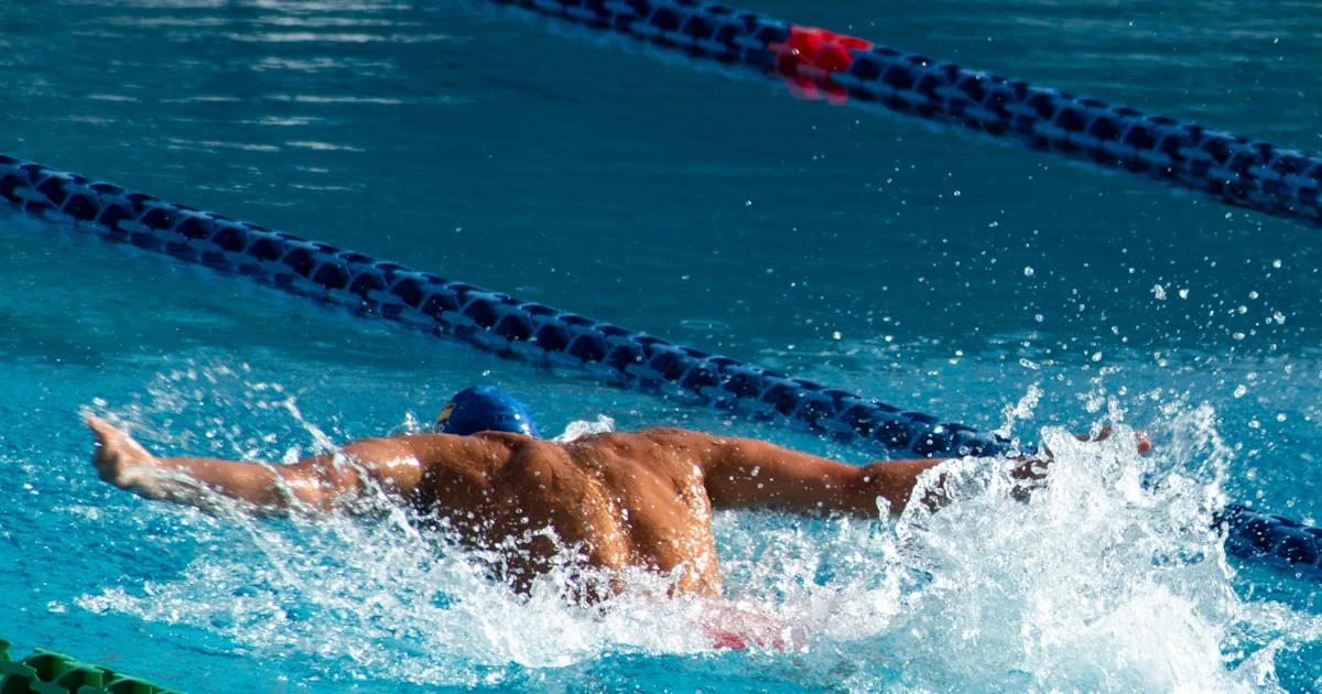 Nageur débutant en piscine qui travaille sa technique de crawl pour préparer un triathlon