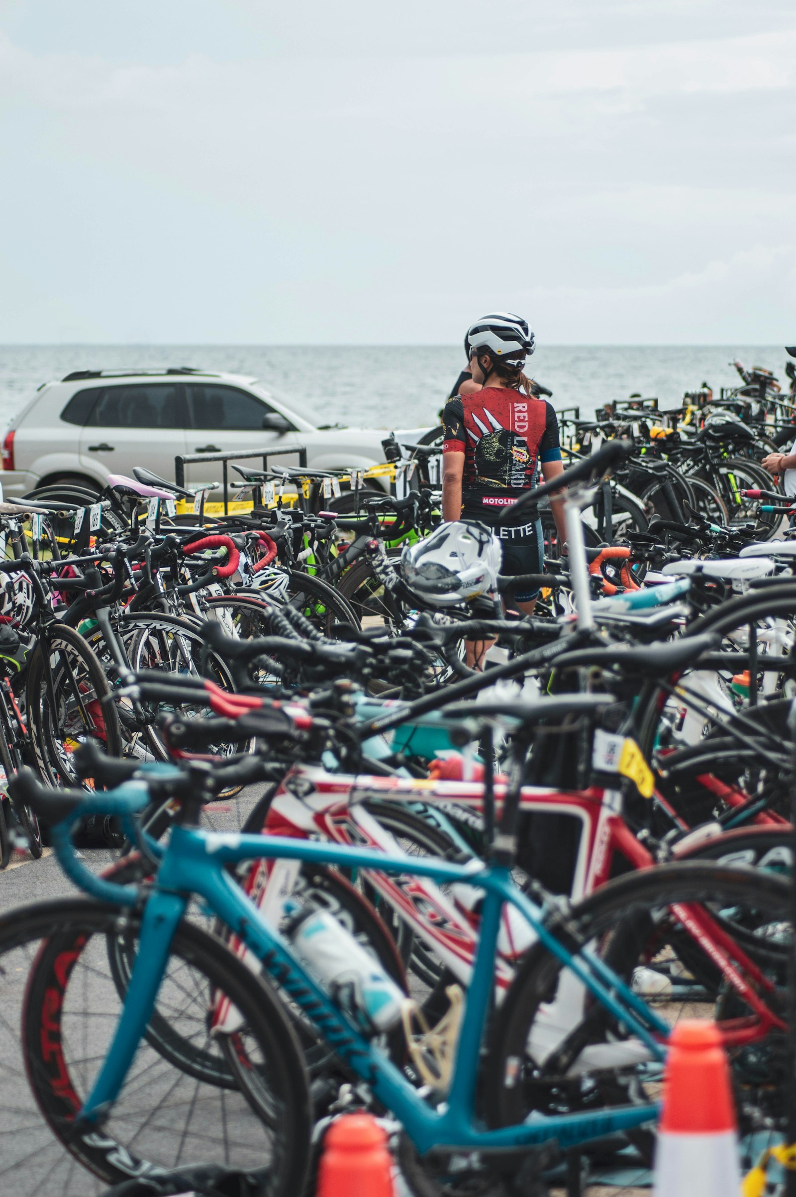 Zone de transition triathlon avec vélos alignés, casques et chaussures posés sur des tapis colorés